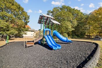 A playground with a blue slide and a green roofed structure