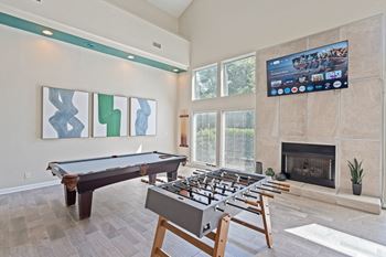 A pool table with a television above it in a room with a fireplace