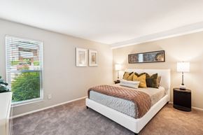 Cary apartment for rent - A bedroom with a large bed and a window with blinds. at Woodcreek Apartments, Cary, NC