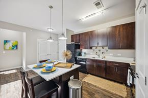 Louisville apartment for rent - A modern kitchen with dark wood cabinets and a white island. at AMP Apartments, Kentucky, 40206