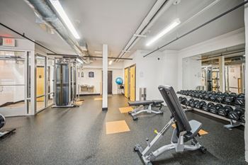A gym with a variety of equipment including weights and a bench