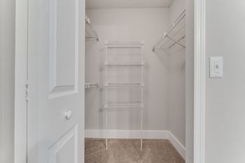 A closet with white shelves and a white door