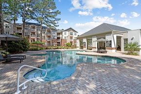 Raleigh apartment for rent - a swimming pool with an apartment building in the background at The Falls Apartments in Raleigh NC