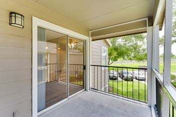 A balcony with a view of a yard and a glass door
