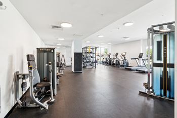 A gym with a variety of equipment including treadmills, weights, and exercise machines