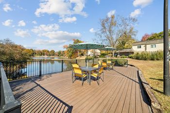 A wooden deck with yellow chairs and a table overlooking a body of water