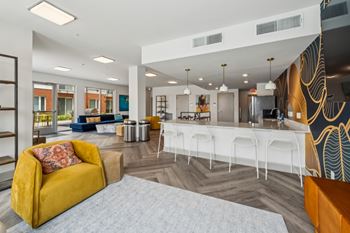 A yellow sofa with a red pillow is in the foreground of a modern living room