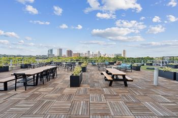 A wooden deck with benches and tables overlooking a city skyline.