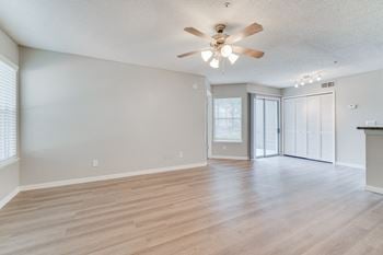 The living room and dining room of an empty house with a ceiling fan