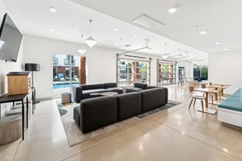 A modern living room with a black sofa and wooden chairs