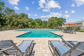 Richmond apartment for rent - A pool surrounded by lounge chairs and umbrellas at Staples Mill Townhomes Apartments, Richmond, VA, 23228