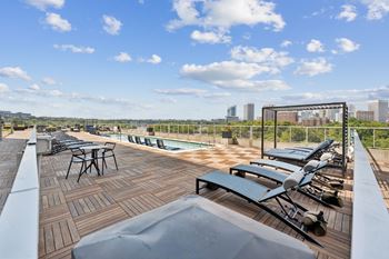 A rooftop patio with a table and chairs overlooking a city skyline.