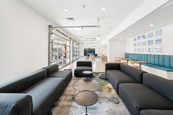 A modern living room with black leather sofas and a glass wall