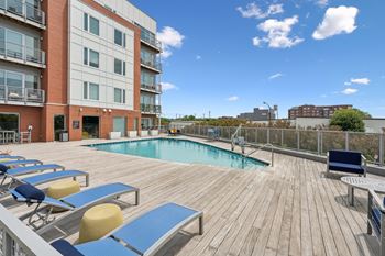 A wooden deck with a pool and sun loungers