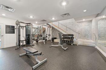 A gym with a variety of equipment including a bench, weights, and a squat rack.