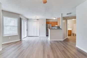 An empty living room and kitchen with a hard wood floor