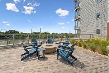 A wooden deck with blue chairs and a table