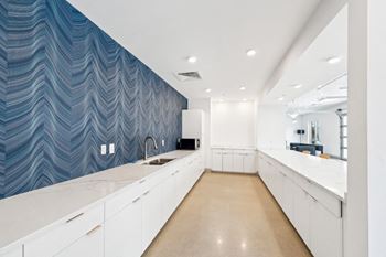 A kitchen with white cabinets and a blue patterned wallpaper