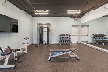 A gym with a variety of equipment including weights and benches