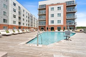 Richmond apartment for rent - a swimming pool in front of an apartment building at The Waterford At Rocketts Landing Apartments, PRG Real Estate, Richmond, Virginia