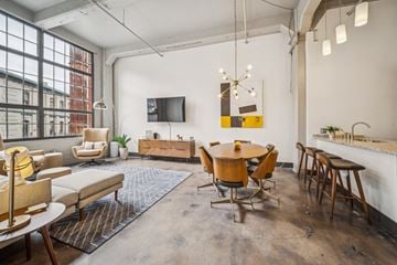 Richmond apartment for rent - A modern living room with a large window, a flat screen TV, and a dining table with chairs.