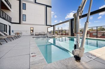 A pool with lounge chairs and a building in the background