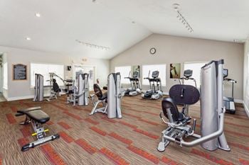 A gym with weights and cardio equipment in a building with white walls