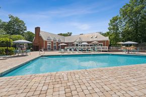 Richmond apartment for rent - A large outdoor swimming pool with a brick patio and a house in the background. at The Timbers Apartments, Virginia