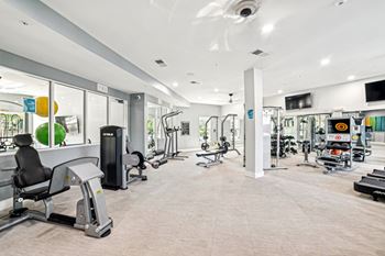 A gym with a variety of equipment including treadmills, weights, and exercise machines.