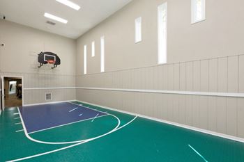A basketball court inside a gym with a basketball hoop mounted on the wall
