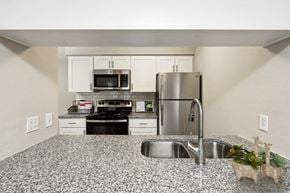 Kansas City apartment for rent - a kitchen with granite counter tops and stainless steel appliances at The Reserve At Barry Apartments, Kansas City