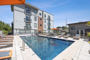 Kansas City apartment for rent - Swimming Pool with Chaise Lounge Chairs and Umbrellas in Front of a Building at 45 Madison Apartments, Missouri, 64111