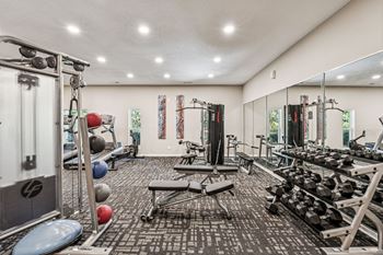 A gym with a variety of equipment including weights and a bench.