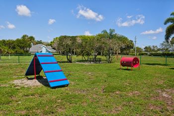 A playground with a blue slide and a red barrel