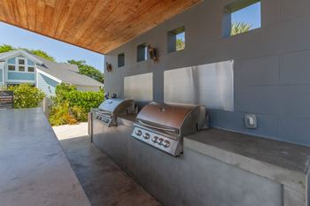 An outdoor kitchen with a grill and a wooden ceiling