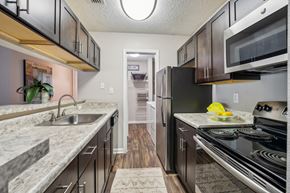 Richmond apartment for rent - A kitchen with black appliances and a marble countertop. at The Timbers Apartments, Richmond 23235
