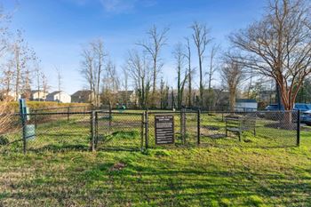 A dog park with a fence and a sign in the grass