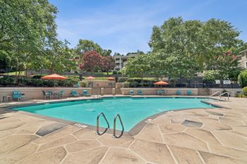 A swimming pool surrounded by trees and chairs