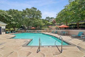 A pool surrounded by trees and chairs