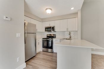 An empty kitchen with white cabinets and stainless steel appliances
