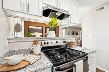 A modern kitchen with a stove top oven and a cutting board with a bowl and utensils on it.