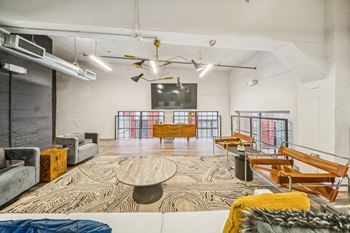 A modern living room with a large rug, a white couch, and a wooden coffee table