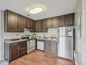 Raleigh apartment for rent - A kitchen with wooden cabinets and a refrigerator at The Falls Apartments in Raleigh NC