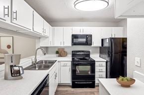 Chapel Hill apartment for rent - A modern kitchen with white cabinets and black appliances.at Chapel View, Chapel Hill, NC