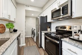 Raleigh apartment for rent - a kitchen with white cabinetry and black appliances  at Lake Johnson Mews, Raleigh