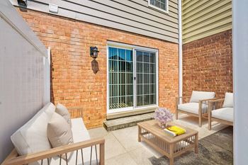 A patio with a table, chairs, and a window with bars.