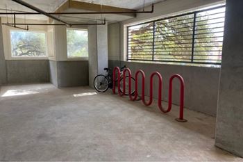 A bicycle is parked in a concrete room with red bike racks.