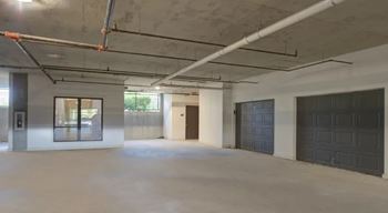 A large, empty room with a concrete floor and ceiling, and a few windows.