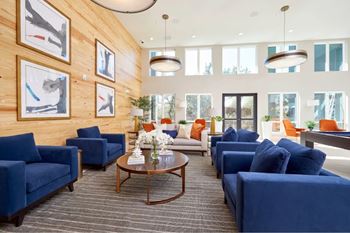 A living room with blue couches and wooden walls.