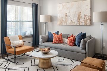Cumming apartment for rent - A living room with a grey couch, a chair, a coffee table, and a large painting on the wall.